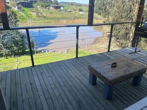 Enjoy the serene river views from this elevated deck, featuring a bench for relaxation and a metal railing for safety.