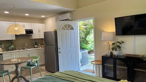 A modern kitchen with white cabinets, a stainless steel refrigerator, and a dining area with a table and chairs. - Palmy Jungalow, a Serene Studio, Mount Dora (Mount Dora)