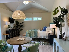 Ein Schlafzimmer mit einem Bett, Nachttischen, einer Pendelleuchte und einem Fenster.