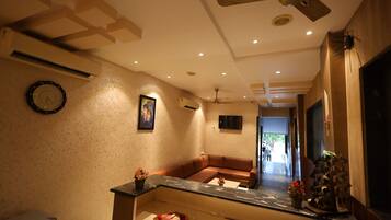 A modern living room with a brown leather sofa, a glass coffee table, and a ceiling fan.