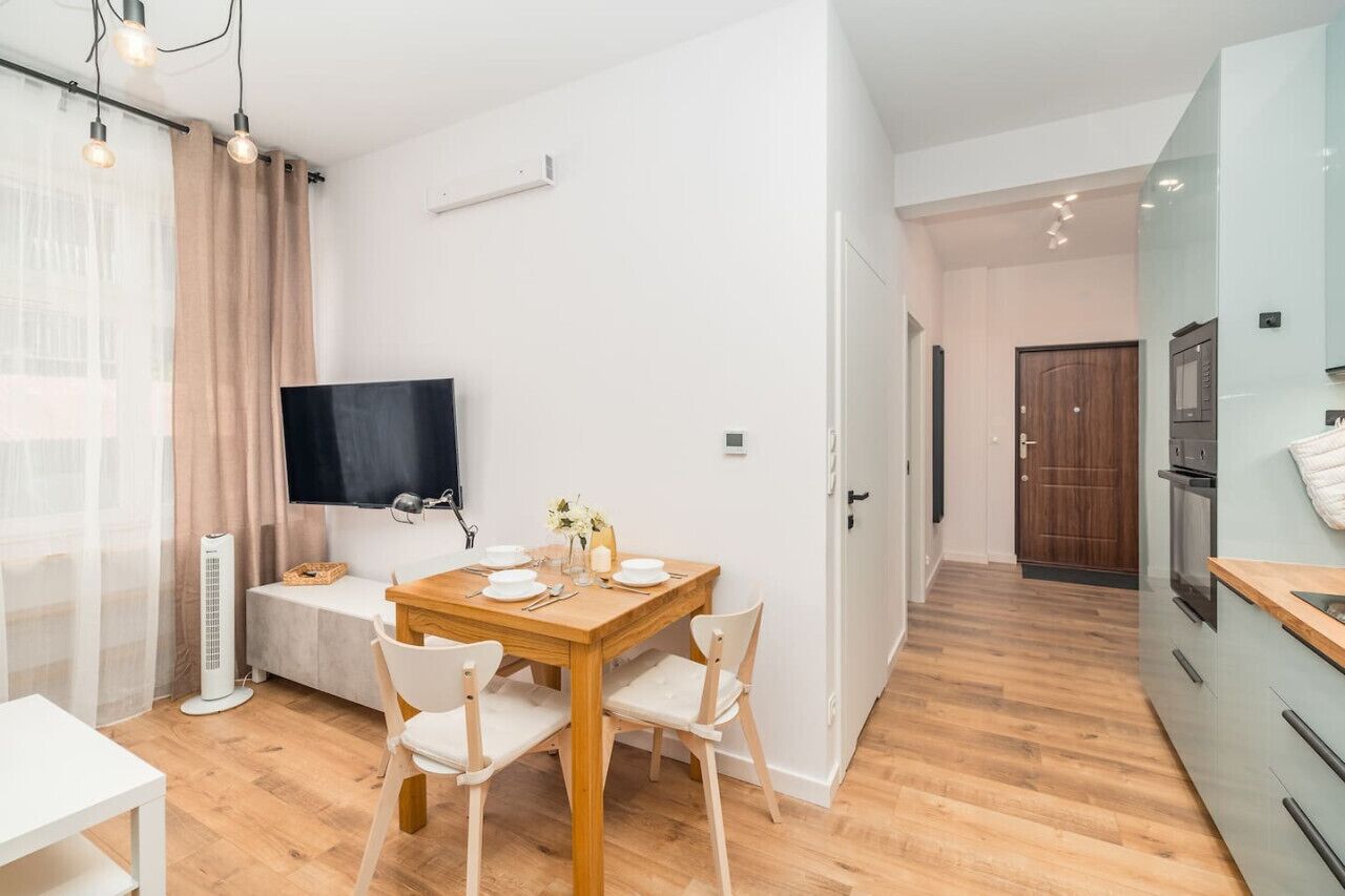 Eine moderne Küche mit Einbauofen und Essbereich mit Holztisch und weißen Stühlen.