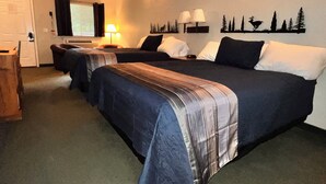 A hotel room with two single beds, a desk, a chair, a lamp, and a wall decoration. - Cozy studio in charming Bellaire with AC, WiFi (Bellaire)