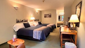 A hotel room with two beds, a desk, a chair, a trash bin, and a small table with a tissue box. - Cozy studio in charming Bellaire with AC, WiFi (Bellaire)
