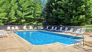 A rectangular swimming pool with a metal ladder on one side, surrounded by white lounge chairs and a fence. - Cozy studio in charming Bellaire with AC, WiFi (Bellaire)
