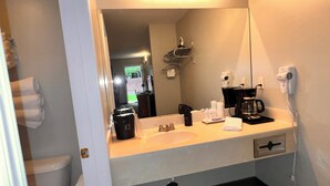 A bathroom with a sink, mirror, and toiletries. - Cozy studio in charming Bellaire with AC, WiFi (Bellaire)