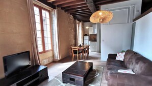 A living room with a TV, sofa, coffee table, and a dining area with chairs and a table.