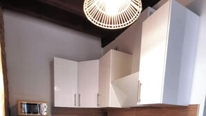 A compact kitchen with white cabinets, a black countertop, a built-in microwave, a coffee maker, and a black induction cooktop.