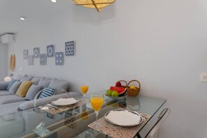 Ein modernes Wohnzimmer mit einem Glastisch, einer Couch mit Kissen und Wandbildern.
