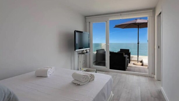 A hotel room with a bed, a TV, and a balcony with a view of the sea. - Carvajal Beach Apartment. Maravillosas Vistas (Benalmádena)