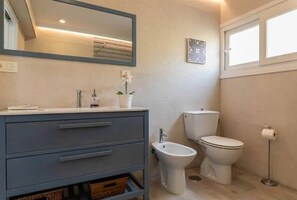 Ein Badezimmer mit grauem Waschtisch, einem Bidet, einer Toilette und einem Toilettenpapierhalter.