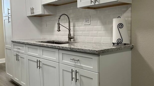 A kitchen with white cabinets, a granite countertop, a stainless steel faucet, and a paper towel holder. - Modern Lauderhill Condo/ Private Room and Bathroom (Lauderdale Lakes)