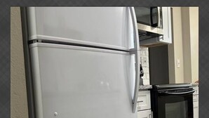 A kitchen with a white refrigerator, a microwave, and a black oven. - Modern Lauderhill Condo/ Private Room and Bathroom (Lauderdale Lakes)