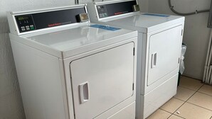 Two white front-loading washing machines in a laundry room with tiled flooring and a white wall. - Modern Lauderhill Condo/ Private Room and Bathroom (Lauderdale Lakes)
