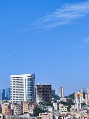 A cityscape with modern high-rise buildings, including a distinctive curved building and a rectangular building with a grid pattern. - Guangzhou Hantao International Apartment (Guangzhou)