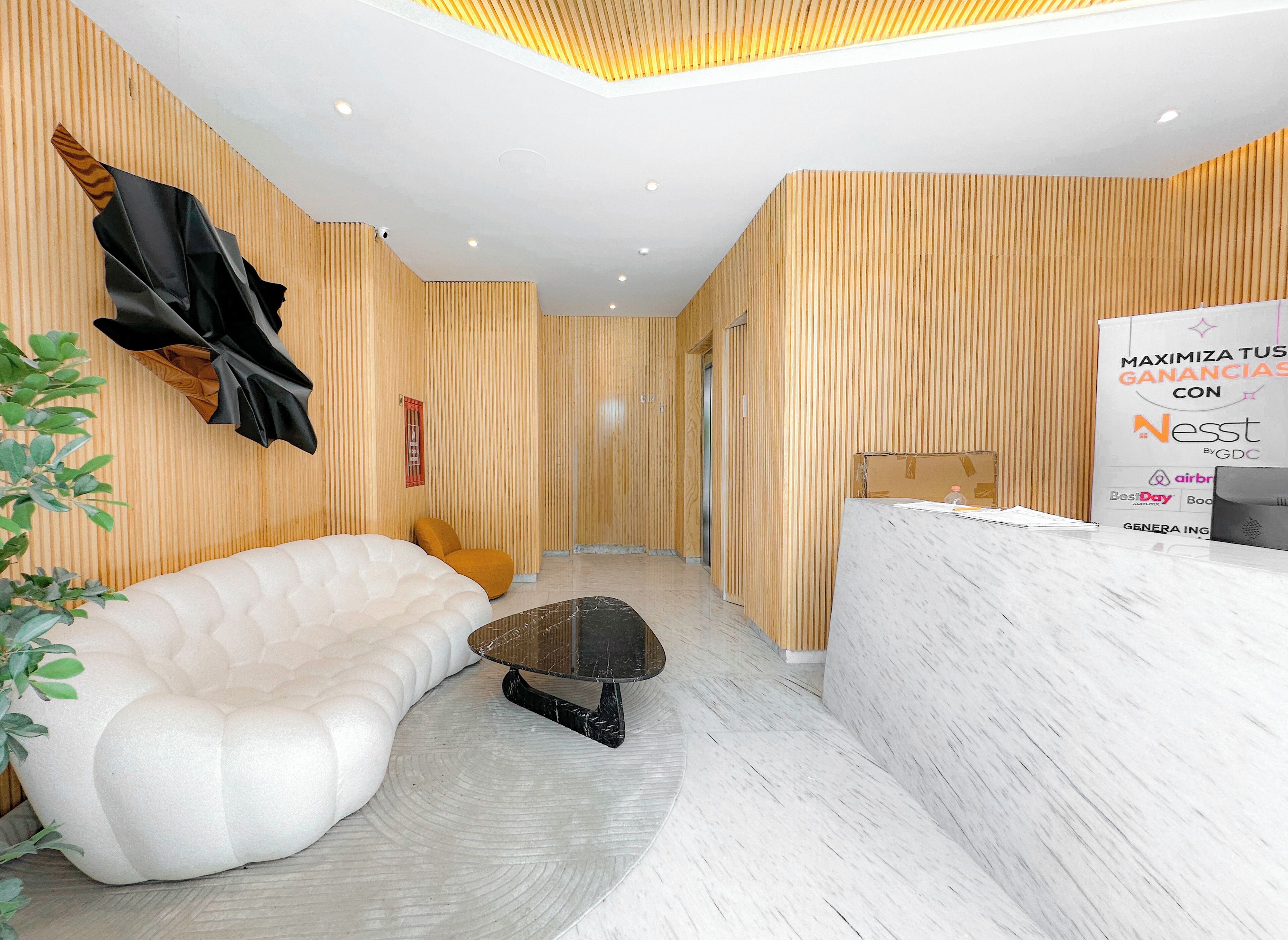 A modern reception area with a white reception desk, a plush white sofa, and a small black coffee table.