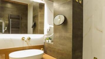 A modern bathroom with a large mirror, a round sink, and a bathtub.