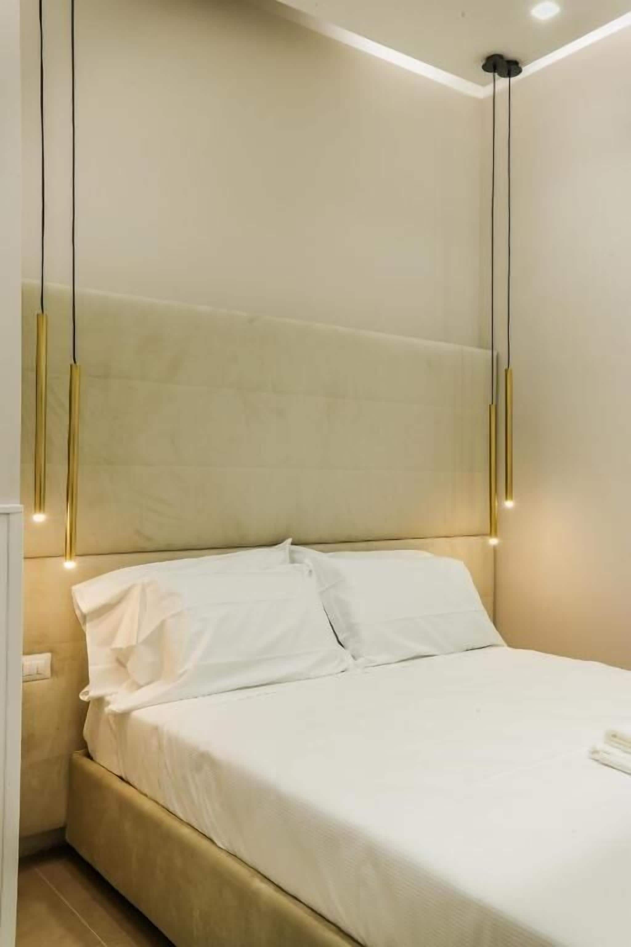A neatly made bed with white linens and a beige headboard in a hotel room.