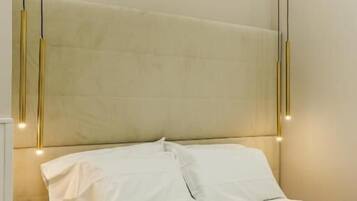 A neatly made bed with white linens and a beige headboard in a hotel room.
