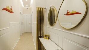 A hallway with white walls, a bench, and two decorative wall mirrors. - Conte Relais Suite (Naples)
