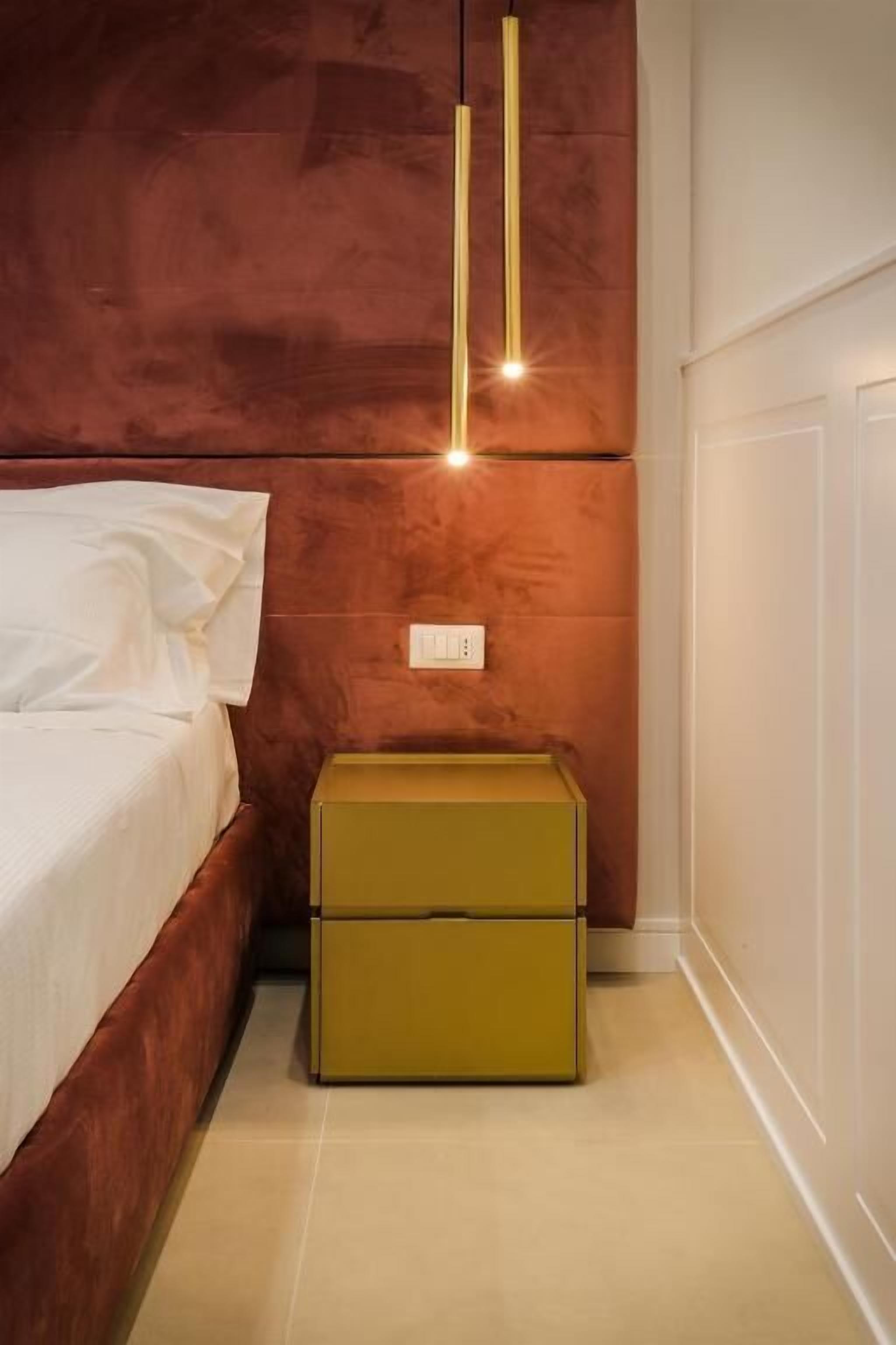 Un dormitorio con cama, mesita de noche y una lámpara fijada a la pared.