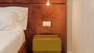 Un dormitorio con cama, mesita de noche y una lámpara fijada a la pared.