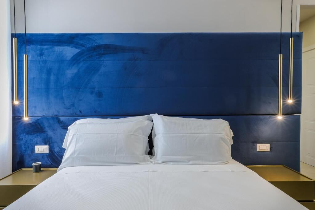 A modern hotel room with a large bed, white bedding, and a blue accent wall.