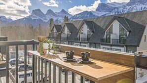 Ein Balkon mit einem Holztisch, zwei Tassen und einem Blumentopf.