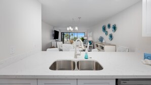 A modern kitchen with a large island, stainless steel sink, and a dishwasher.