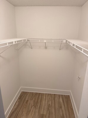 Ein kleiner, leerer begehbarer Kleiderschrank mit Holzboden und weißen Wänden.