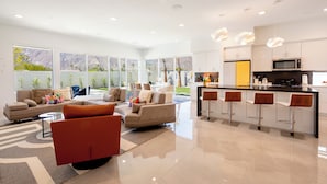 A modern kitchen with white cabinets, a black countertop, and a bar area with stools. - Posh Private Panoramic View Compound w/Pool & Spa (Palm Springs)