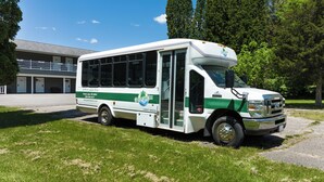 Un autobus blanc et vert est garé devant un bâtiment sur lequel on peut lire l’inscription « Green Lake Inn ».