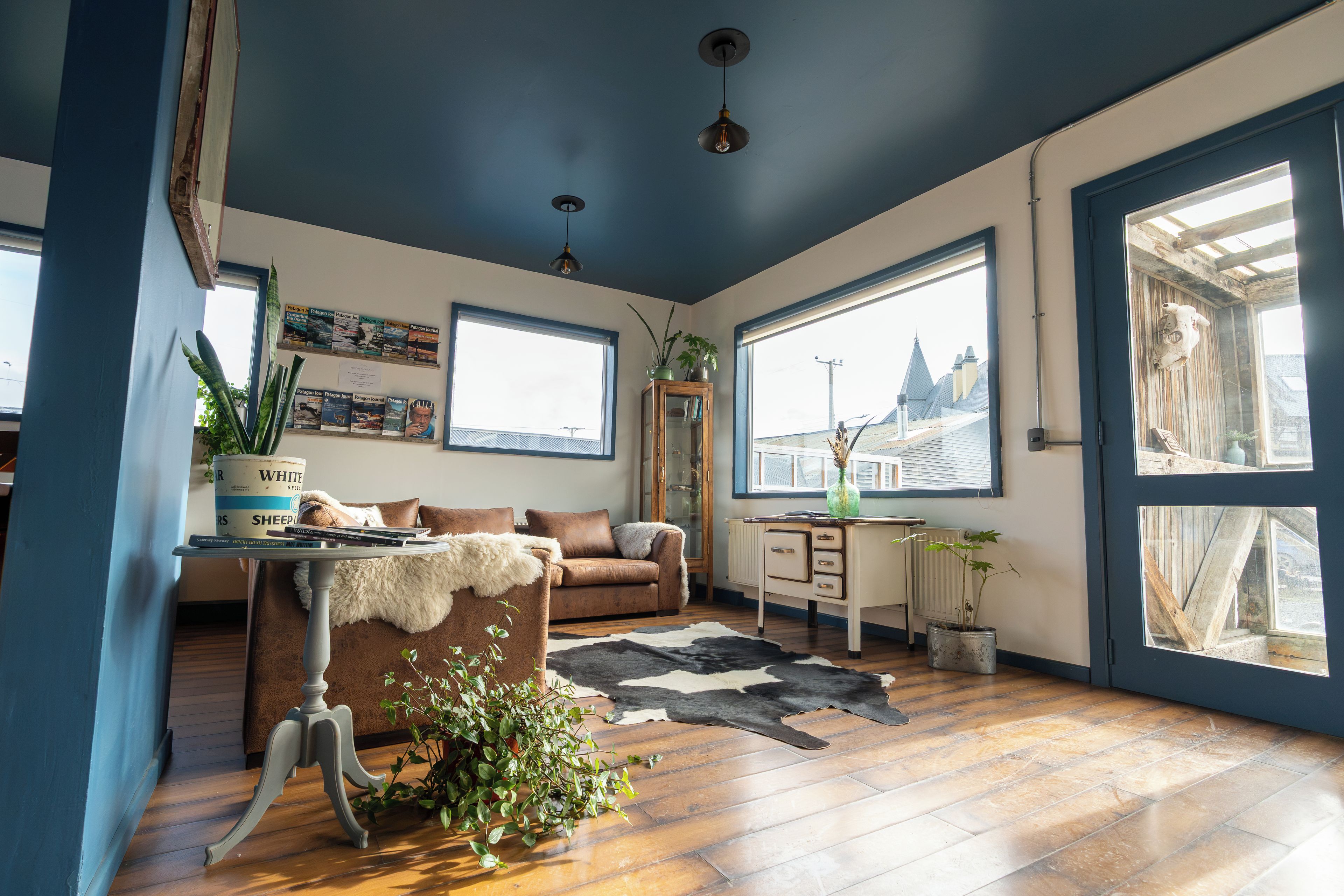 A cozy living room with a brown leather sofa, a coffee table, and a large window.