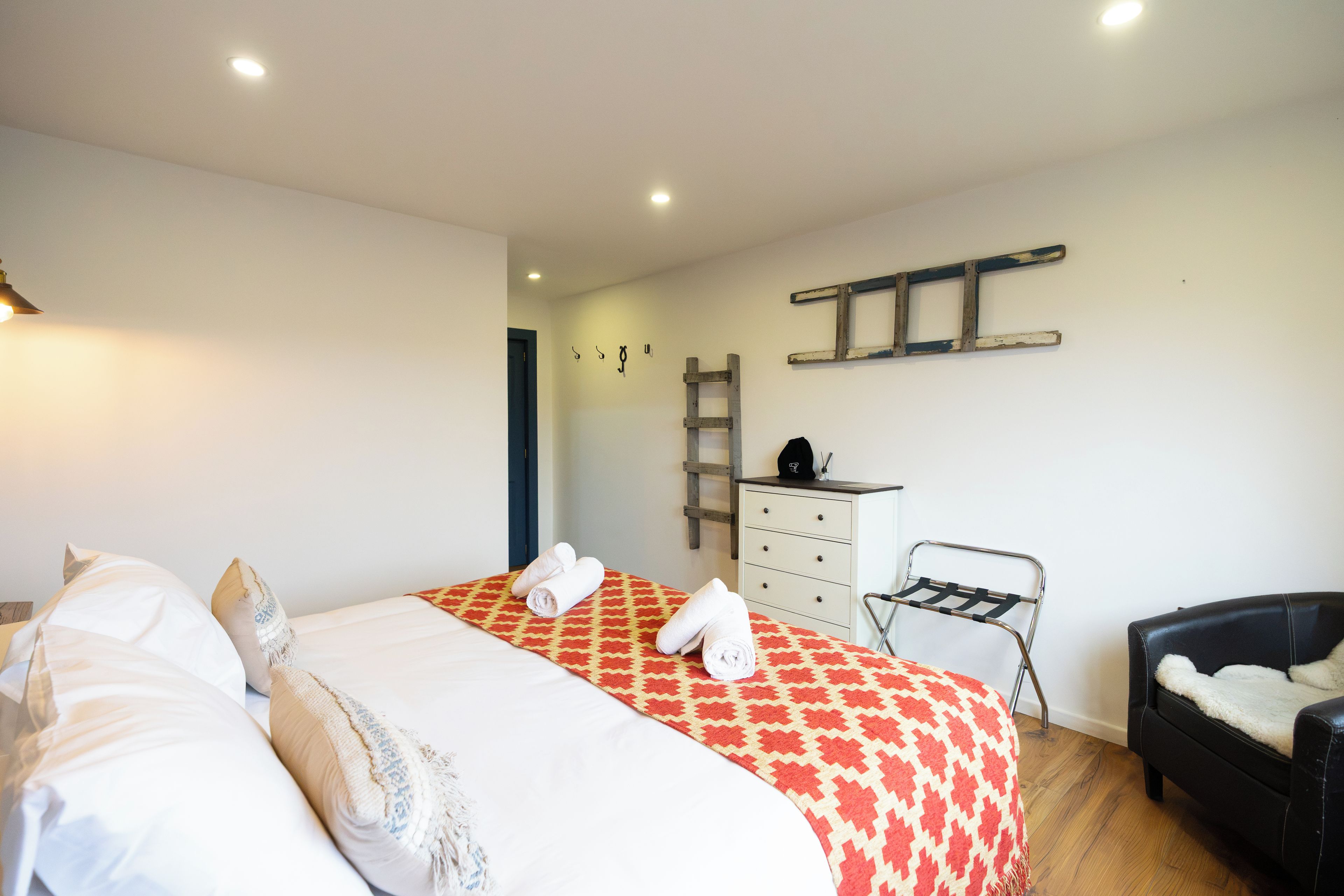 Ein Hotelzimmer mit Bett, Schreibtisch, Stuhl und einer Leiter an der Wand.