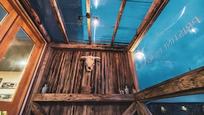 A rustic interior with wooden beams, a cow skull decoration, and a glass ceiling. - Pristine Patagonia Hotel (Natales)