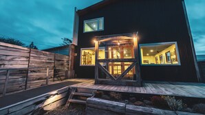 Ein modernes, zweistöckiges Gebäude mit einer Holzterrasse und großen Fenstern.