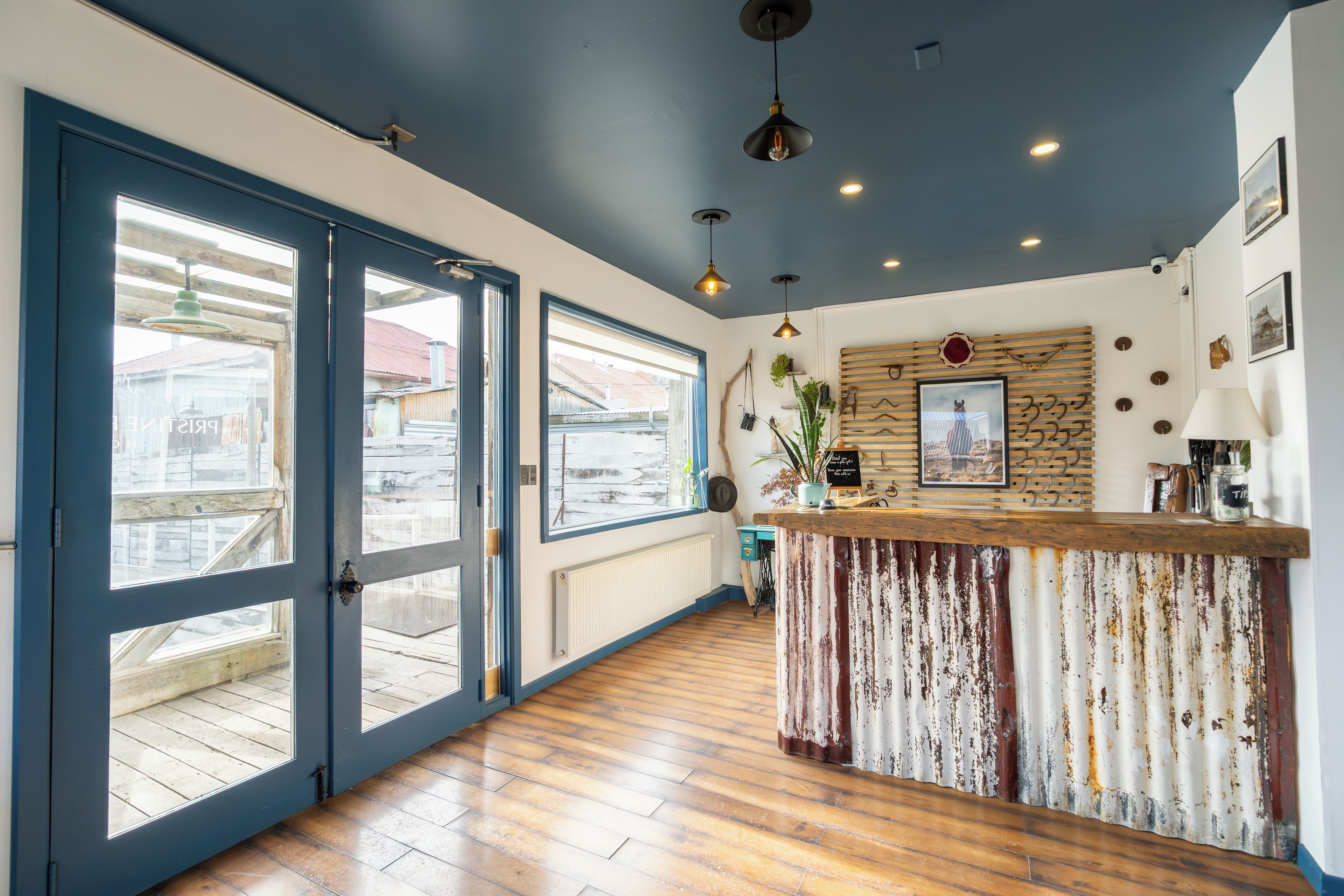 A spacious room with a large sliding glass door leading to an outdoor area, a wooden bar counter, and a ceiling with recessed lighting.