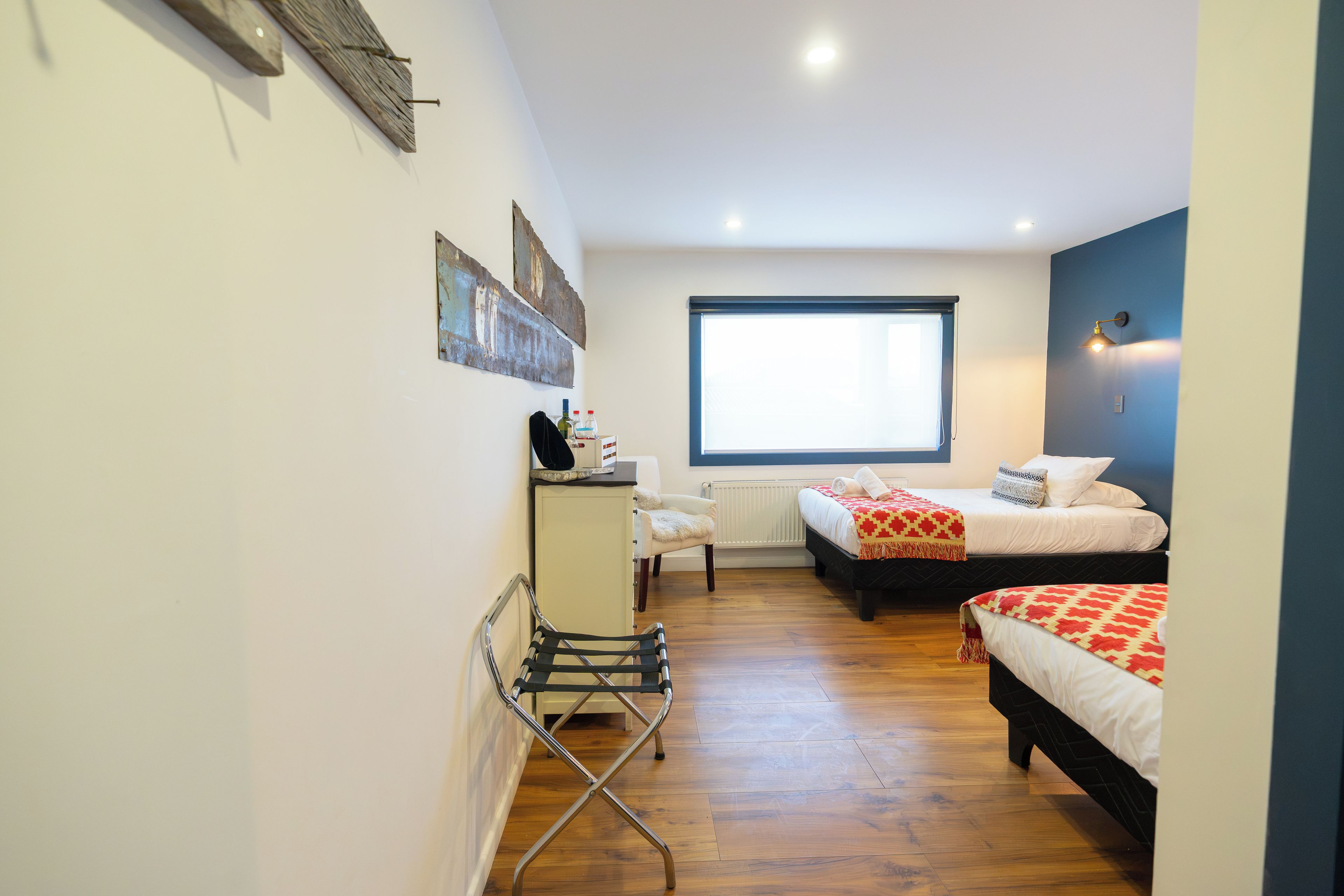 A bedroom with two beds, a desk, a chair, and a window.