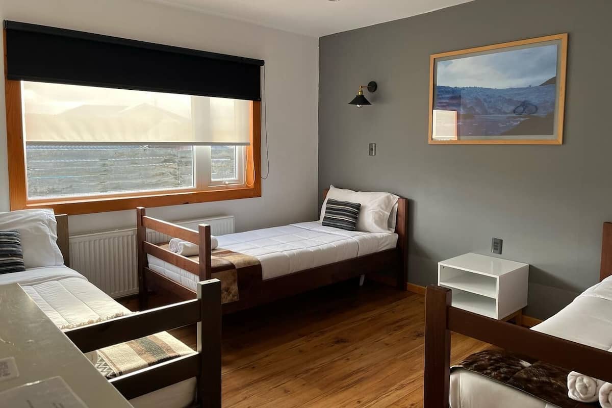 Ein gemütlicher Raum mit einem Bett, einem kleinen Nachttisch, einem Fenster mit Meerblick und einem gerahmten Bild an der Wand.
