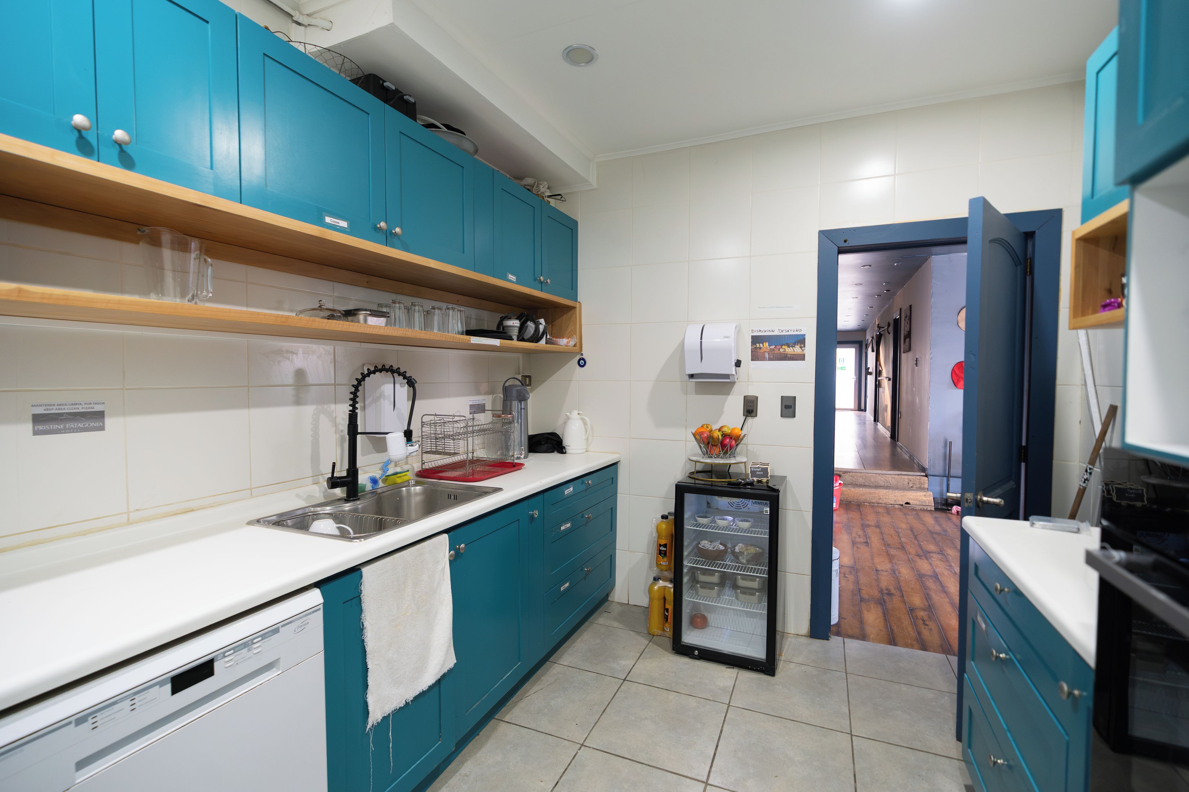 A kitchen with teal cabinets, a white countertop, and a refrigerator.