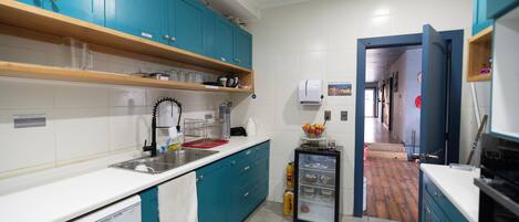 A kitchen with teal cabinets, a white countertop, and a refrigerator.