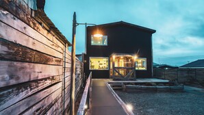 A two-story building with a wooden exterior and a paved entrance area. - Pristine Patagonia Hotel (Natales)