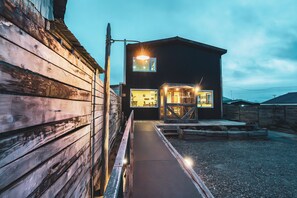 Een gebouw met twee verdiepingen, een houten gevel en een verhard entreegebied.