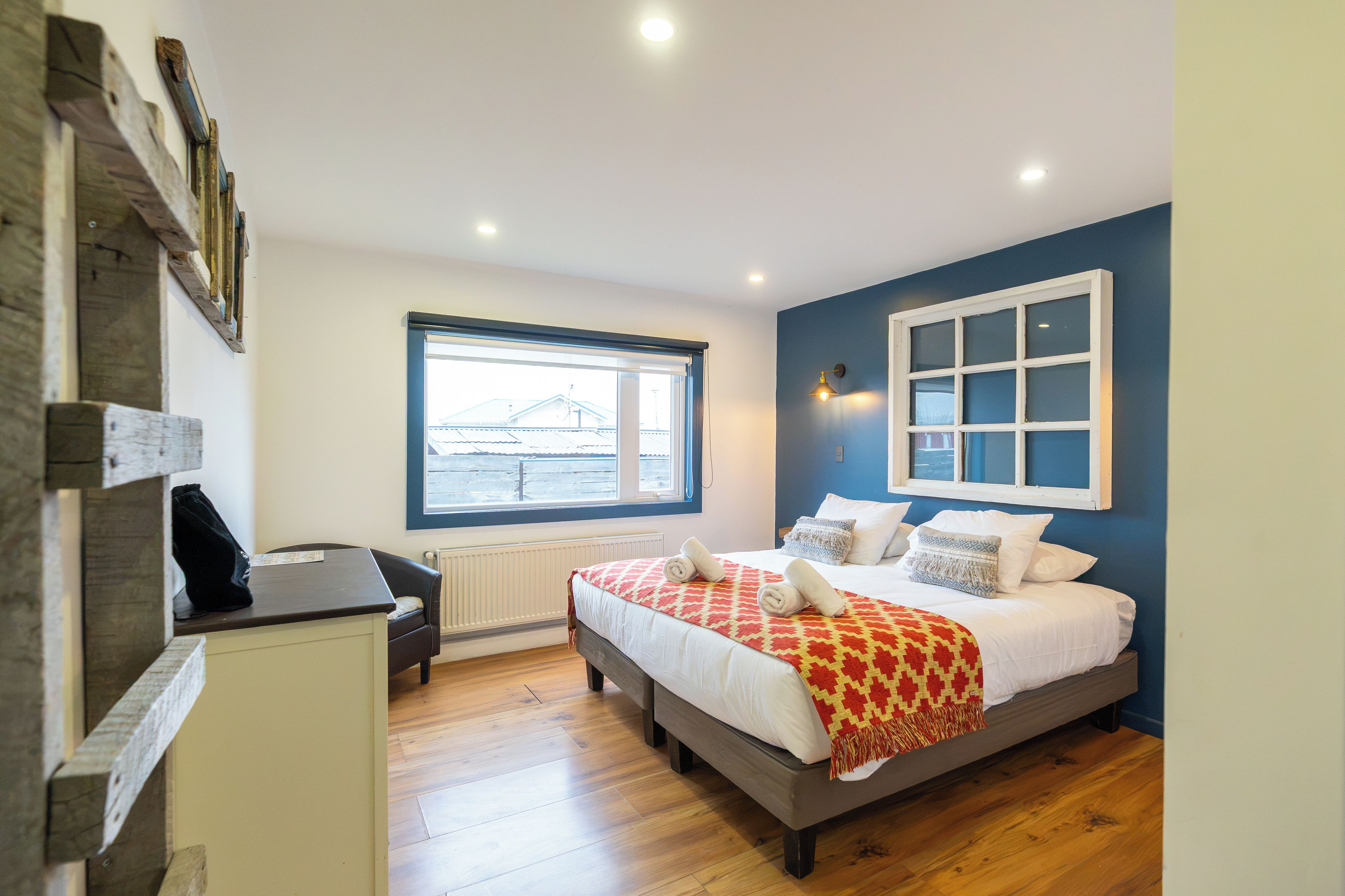 A bedroom with a bed, a desk, a window, and a view of the outside.