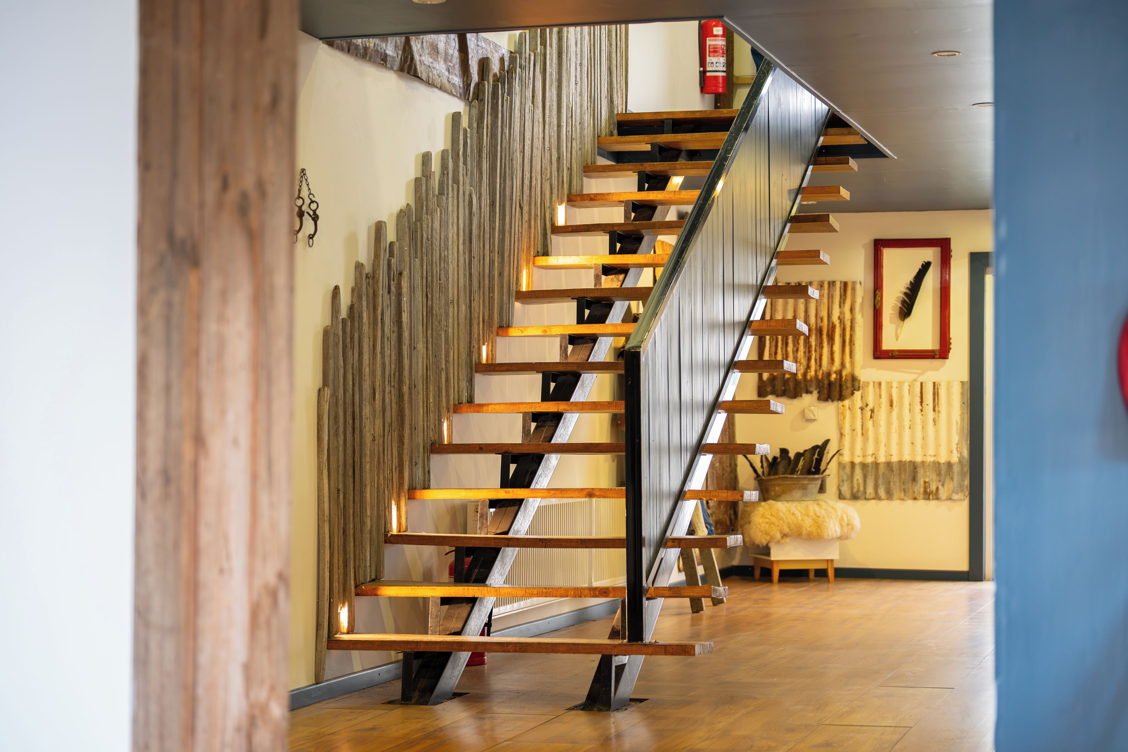 A modern staircase with wooden steps and metal railings, leading to an upper floor.