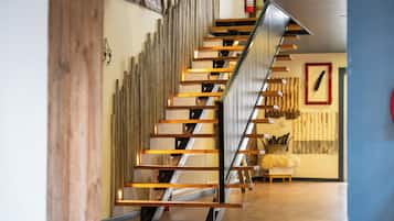 Una escalera moderna con escalones de madera y barandillas de metal, que conduce a un piso superior.
