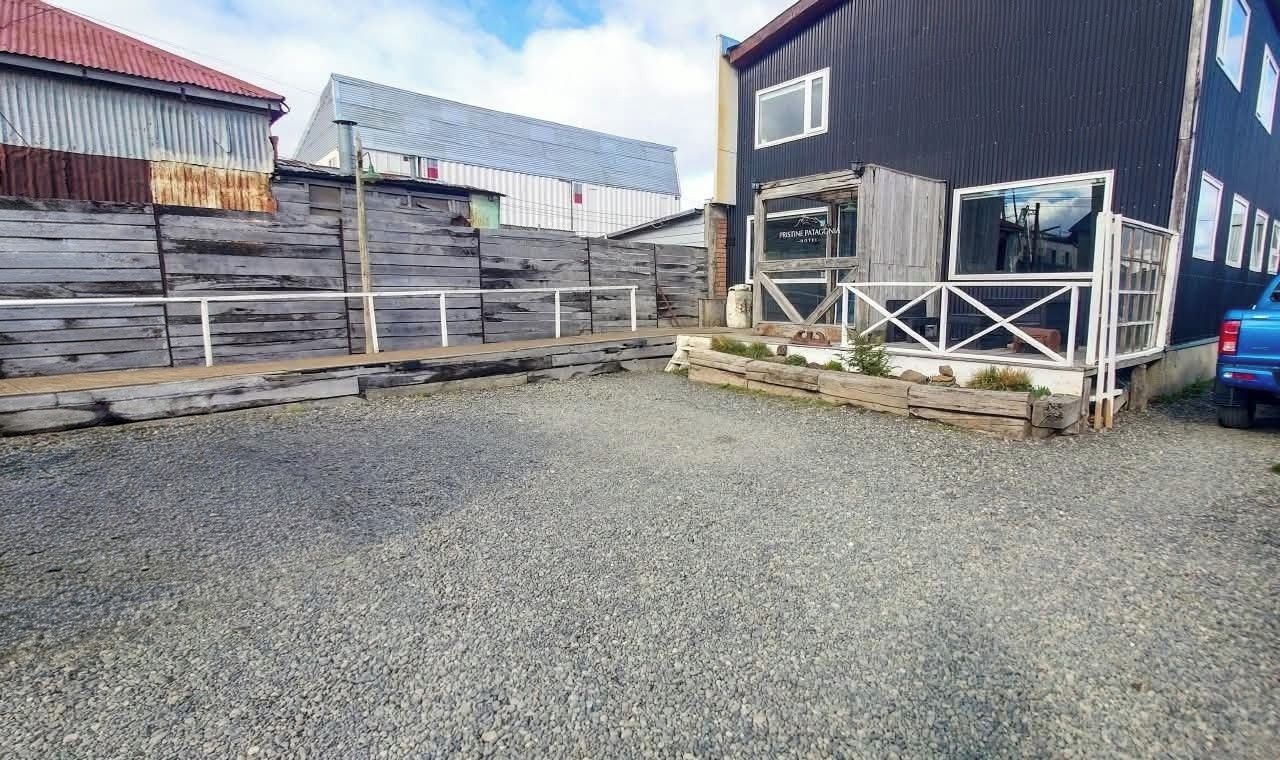 A building with a metal roof, a wooden fence, and a gravel driveway.