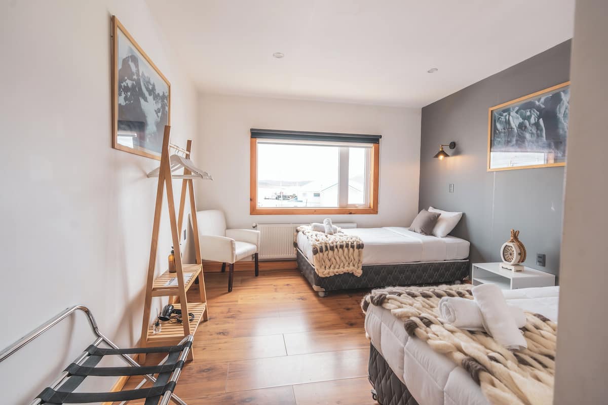 Ein Schlafzimmer mit einem Bett, einem Sessel, einer Leiter, einem Fenster und einem Bild an der Wand.