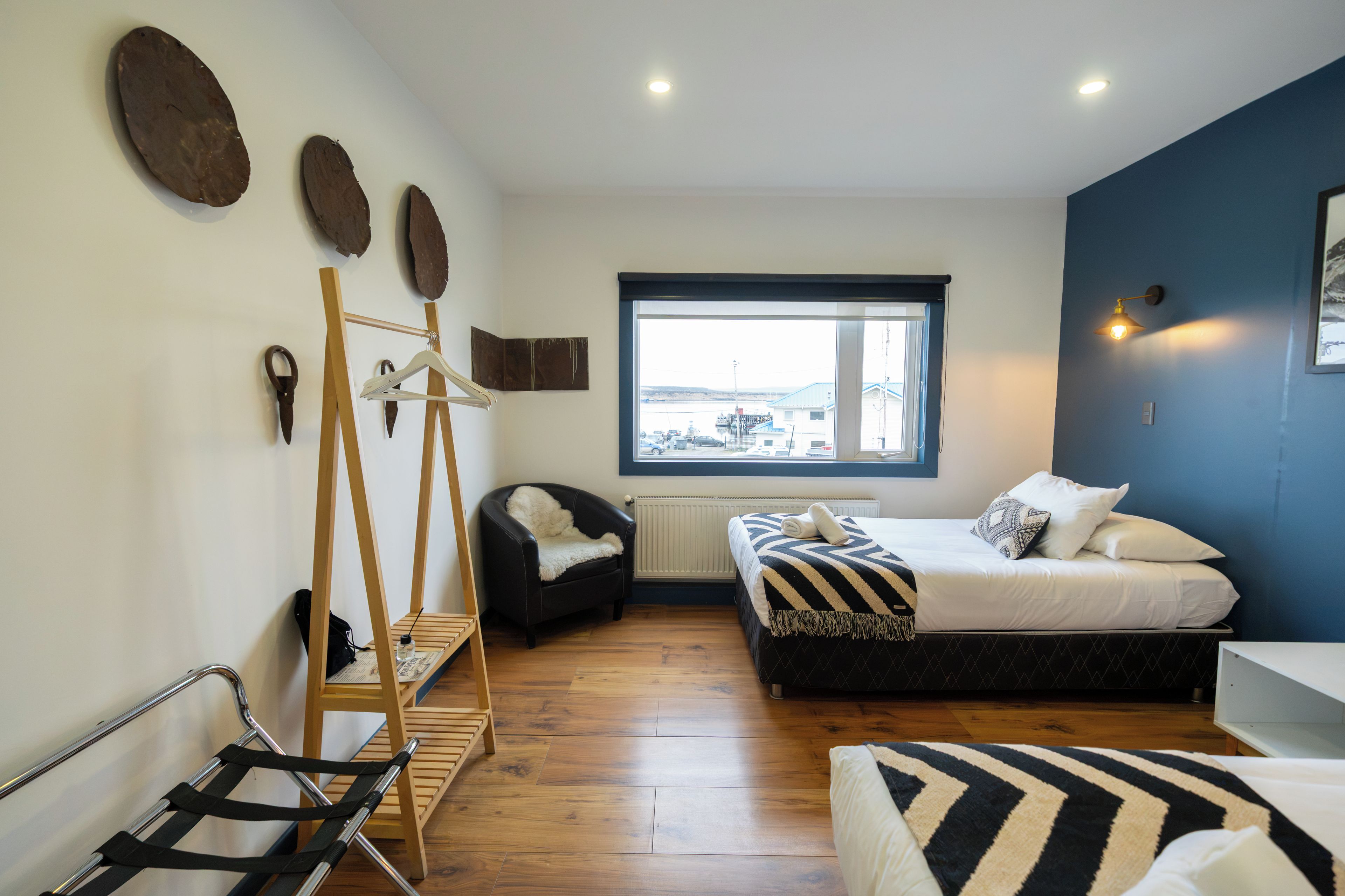 Une chambre à coucher de taille réduite, comprenant un lit, une chaise, un porte-manteau en bois et une fenêtre donnant sur un paysage agréable.
