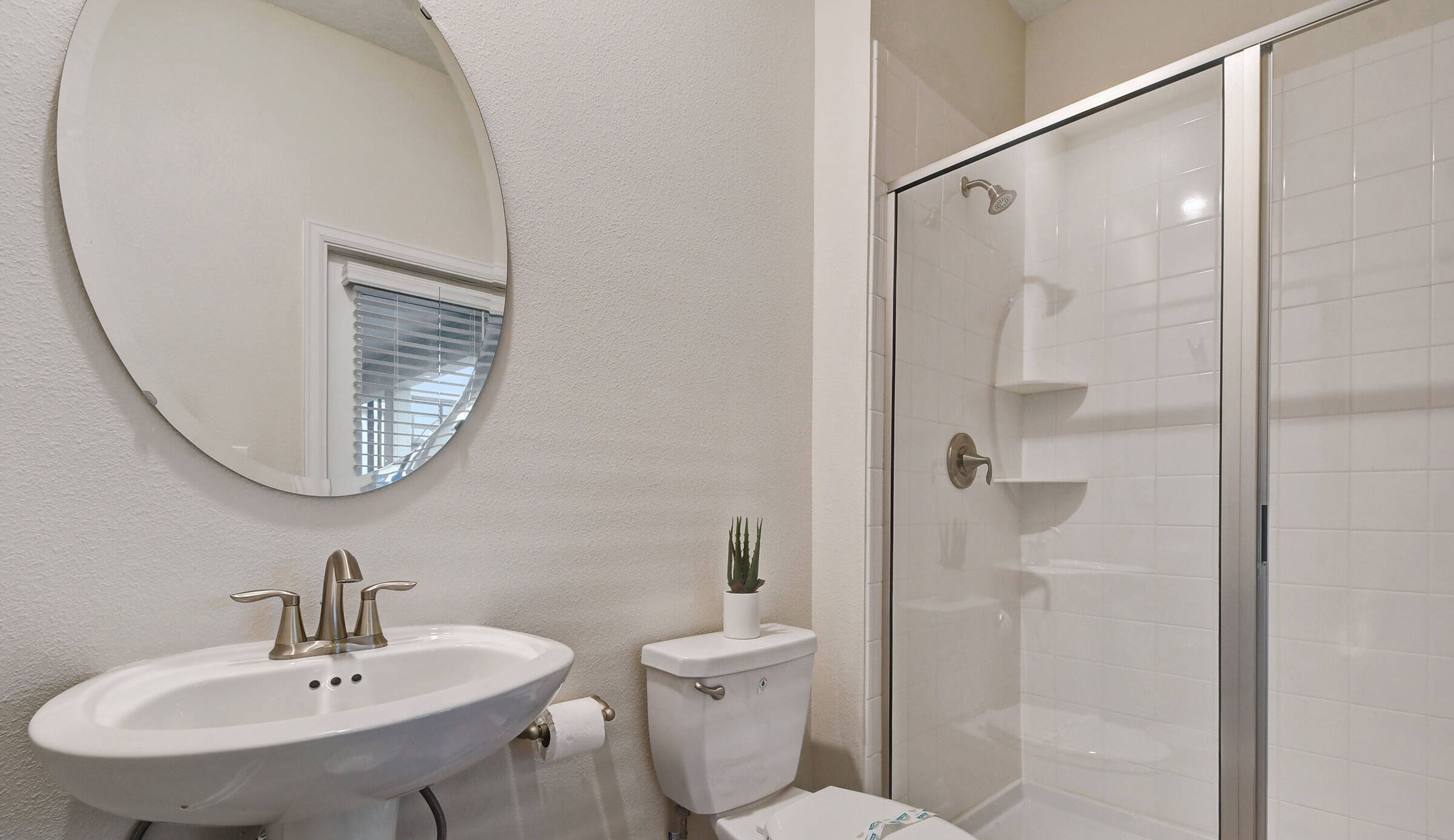 A bathroom with a white sink, toilet, and shower.