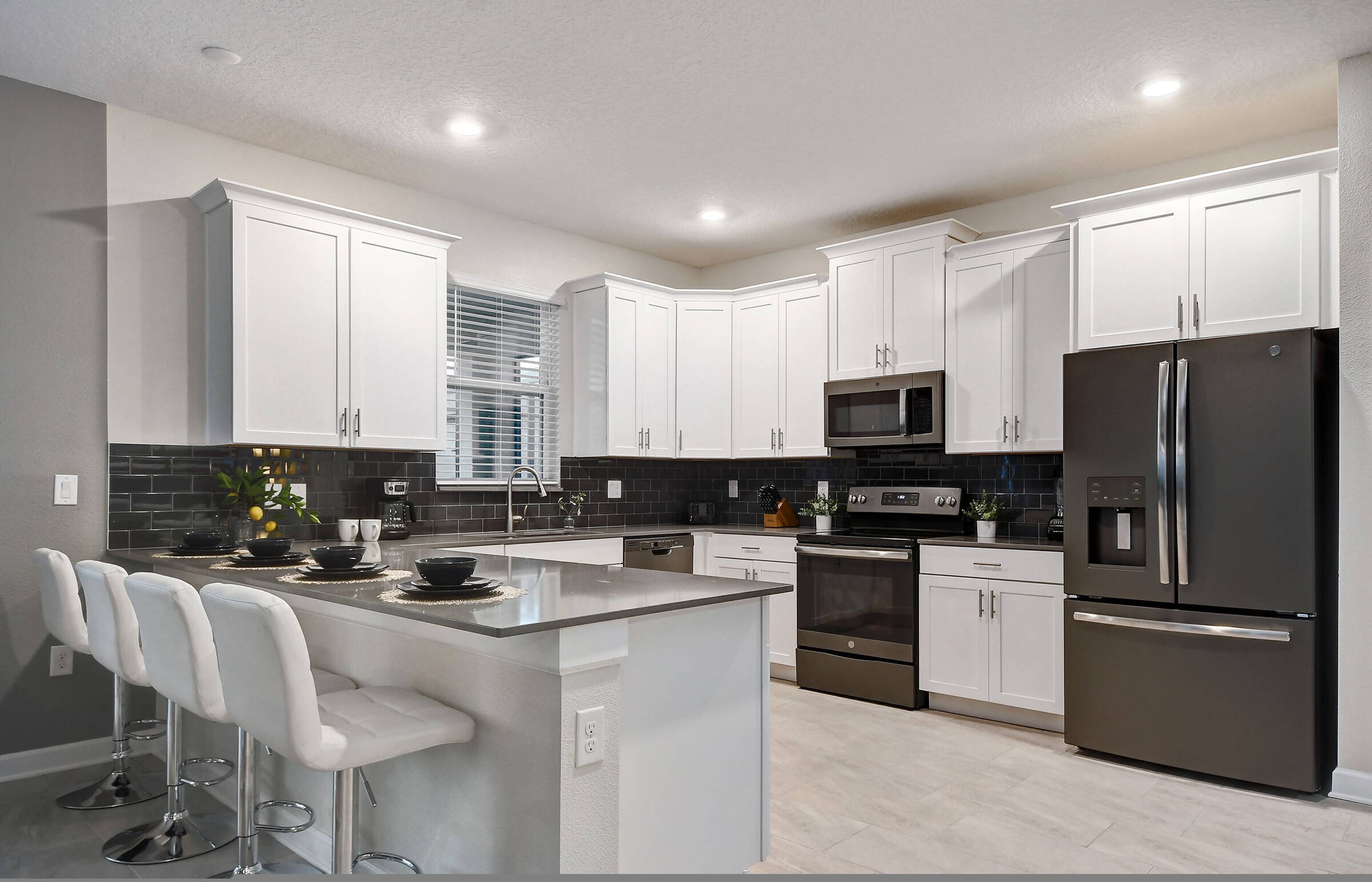 A modern kitchen with white cabinets, stainless steel appliances, and a central island with bar stools.